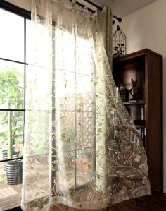 an open window with sheer curtains in front of it and a potted plant next to the window