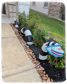 two black and white striped garden hoses on the side of a sidewalk next to plants