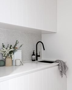 a kitchen with white cabinets and black faucet on the counter top next to a sink