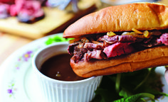 a close up of a sandwich on a plate with dipping sauce in the bowl next to it