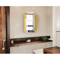 a yellow mirror hanging on the wall above a sink in a bathroom with white walls