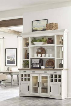 a large white bookcase with glass doors and shelves in a living room next to a dining room table