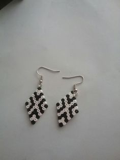 two black and white beads are hanging from silver earwires on a gray surface