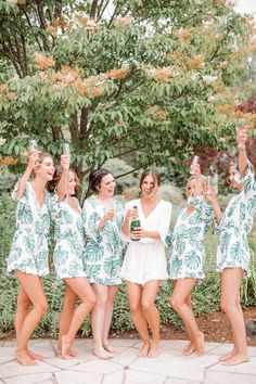 a group of women in green and white robes standing next to each other holding up their cell phones