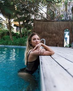 a woman sitting on the edge of a swimming pool