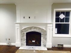 an empty living room with a fireplace in the middle and no one on the floor