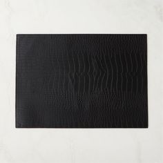 a black leather placemat on a white surface with an embossed pattern in the middle