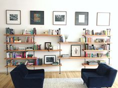 two black chairs sitting in front of a book shelf filled with books and framed pictures