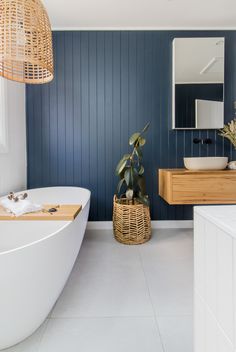 a white bath tub sitting next to a wooden counter top in a bathroom with blue walls