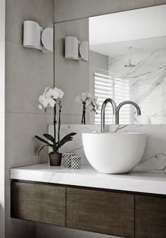 a bathroom sink sitting under a mirror next to a counter top with flowers on it