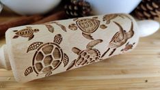 a wooden stamp with sea turtles on it and pine cones in the backgroud