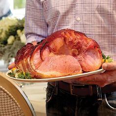 a man holding a plate with ham on it