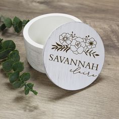 personalized wooden candle holder with flowers and name on the lid next to greenery