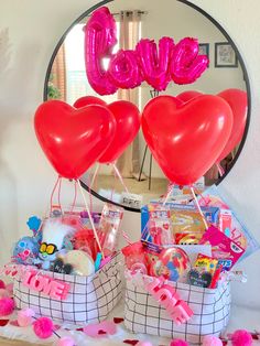 two heart shaped balloons sitting on top of a table next to a basket filled with toys