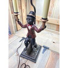 a monkey figurine holding two candles on top of a wooden table next to a wire