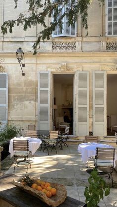 an outdoor dining area with tables and chairs, oranges on a tray in the foreground