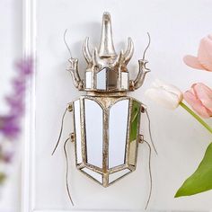 a metal bug with antlers on its back is next to a pink tulip