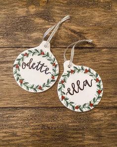 two tags with the word noeltte and an ornament hanging from them on a wooden surface