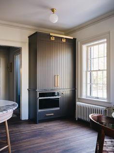 a kitchen with wood flooring and an oven in the corner next to a window