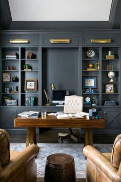 a home office with built - in bookcases, leather chairs and a desk