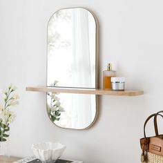 a mirror on the wall above a table with a purse and vase in front of it