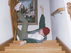 a man is falling down the stairs with his foot in the air while wearing a red hat