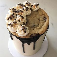 a chocolate chip cookie with white frosting and sprinkles is on top of a cupcake