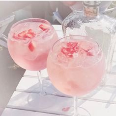 two glasses filled with pink liquid sitting on top of a table