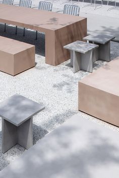 an outdoor seating area with several benches and tables in the middle, surrounded by gravel