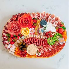 a platter filled with meats, cheeses and vegetables on a marble surface