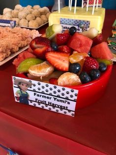 a bowl full of fruit sitting on top of a table next to other desserts