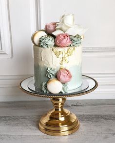 there is a cake with flowers on the top of it and gold plated stand