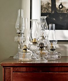 an assortment of glass vases and other items sit on a table in front of a framed photograph