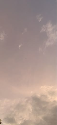 an airplane is flying high in the sky above some trees and clouds with a moon behind it