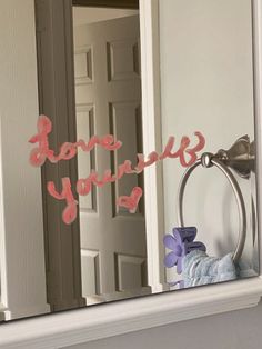 a mirror with some writing on it in front of a door and a towel dispenser