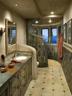 a bathroom with tiled walls and flooring next to two sinks in front of a large mirror