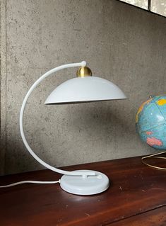 a desk lamp sitting on top of a wooden table next to a small blue globe