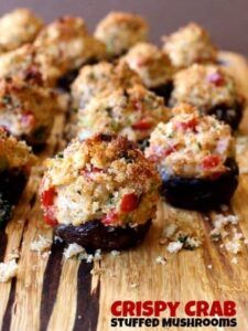 stuffed mushrooms on a cutting board with the words crispy crab stuffed mushrooms above them