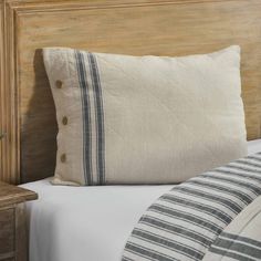 a close up of a pillow on a bed with white sheets and blue striped pillows