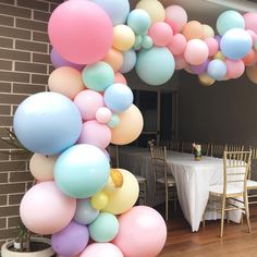 a bunch of balloons are hanging from the ceiling in front of a dining room table