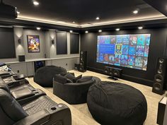 a home theater with black leather chairs and large screen on the wall, surrounded by speakers