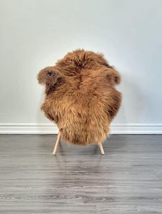 a brown chair sitting on top of a hard wood floor next to a white wall