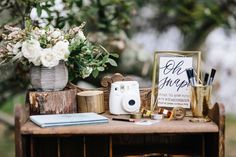 a wooden table topped with lots of different types of items next to a vase filled with flowers