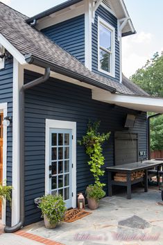 a blue house with white trim and wooden doors is shown in front of a picnic table