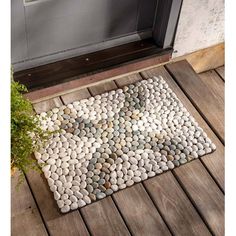 a door mat made out of rocks on a wooden deck