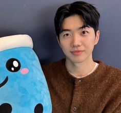 a young man is holding up a stuffed animal that looks like a blue monster with black eyes