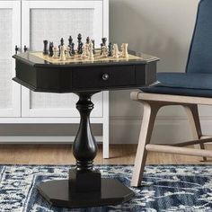 a black chess set sitting on top of a wooden table next to a blue chair