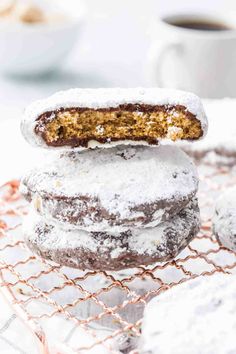 powdered sugar covered cookies stacked on top of each other next to a cup of coffee