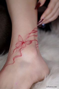 a woman's foot with a red bow tattoo on it