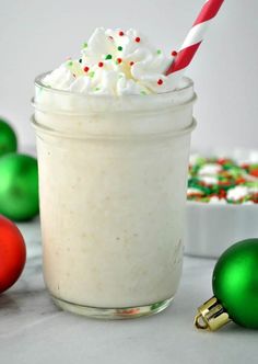 a glass filled with whipped cream surrounded by christmas ornaments